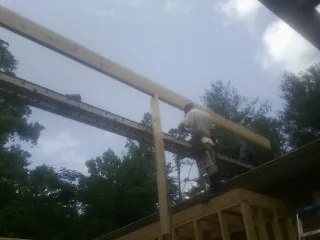 Carpenter setting a ridge beam over a new addition frame — Ice Dam Removal by Roofing Brothers in Delaware