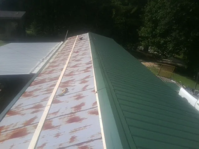 Old rusted panels beside newly installed green metal roofing — Wind Damage Roof Repair by Roofing Brothers in Delaware