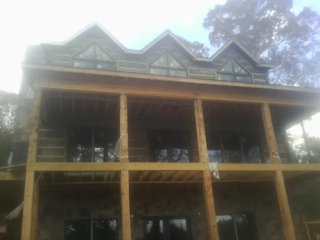 Dormers and porch framing on a large log home under construction — Roof Coating work by our crew in Delaware